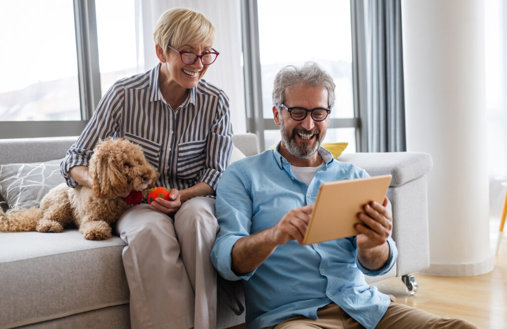 Happy smiling mature couple using digital tablet at home
