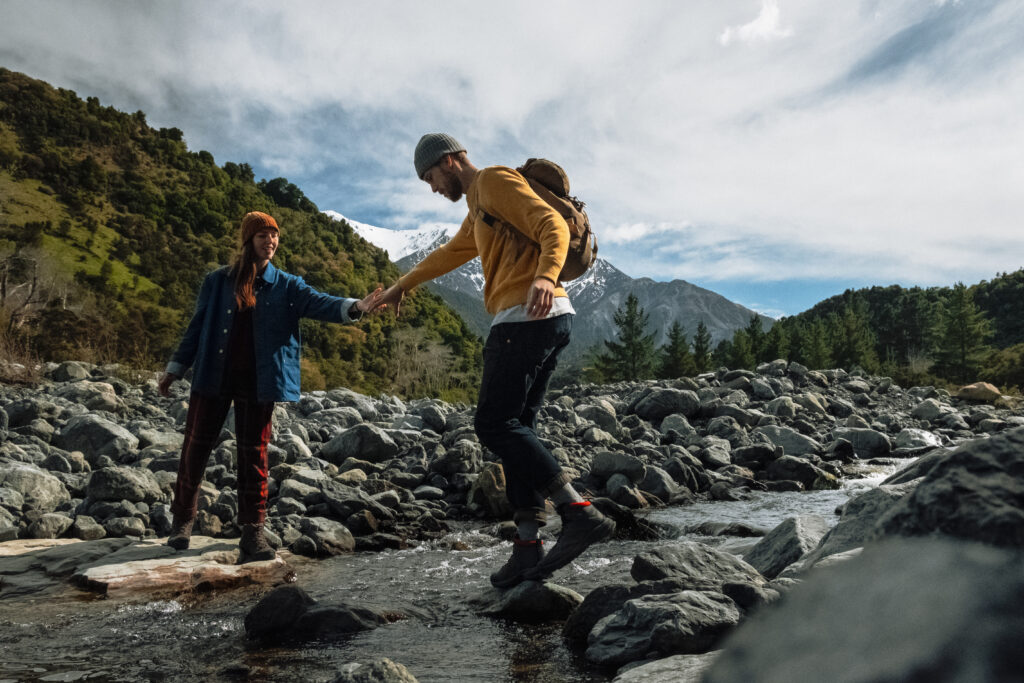 A couple stepping on stones to cross a river