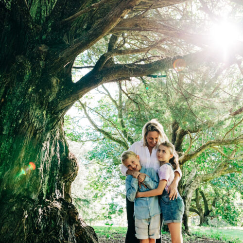 Mother and two children enjoying themselves next to a tree
