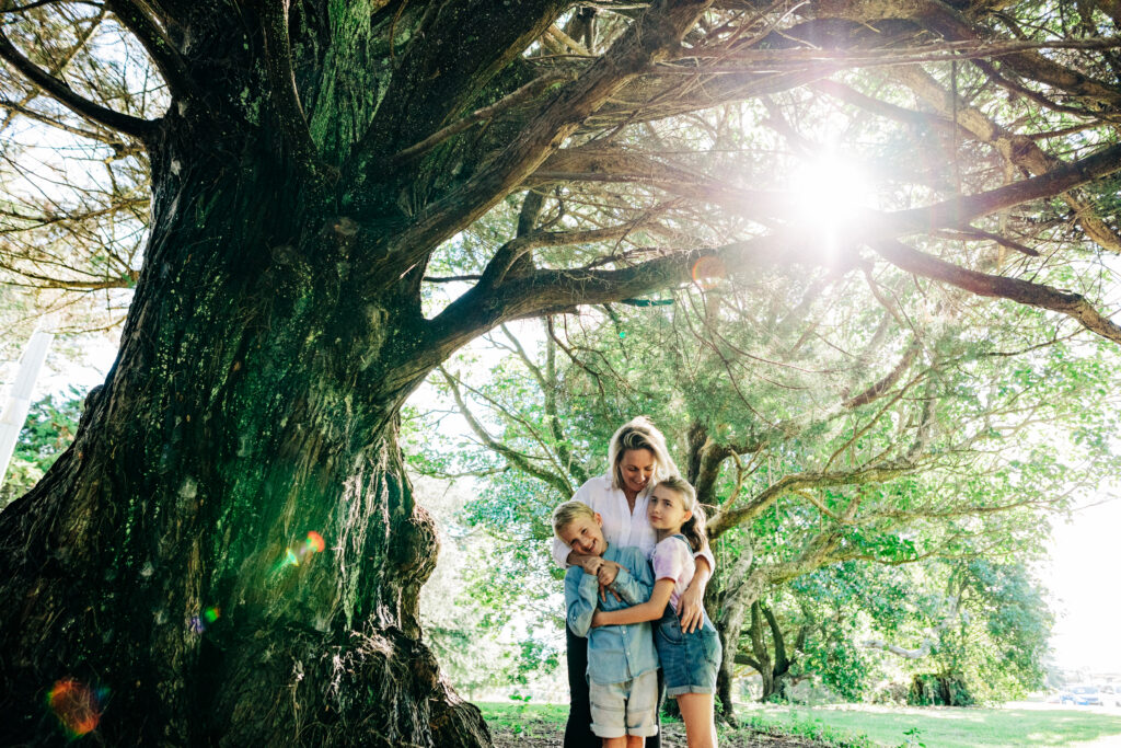 Mother and two children enjoying themselves next to a tree