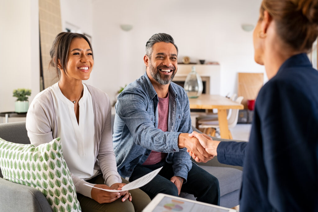A smiling couple shaking hands with a financial coach