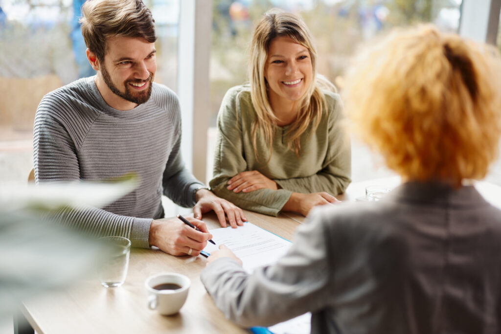 Happy couple talking to their financial coach in the office.