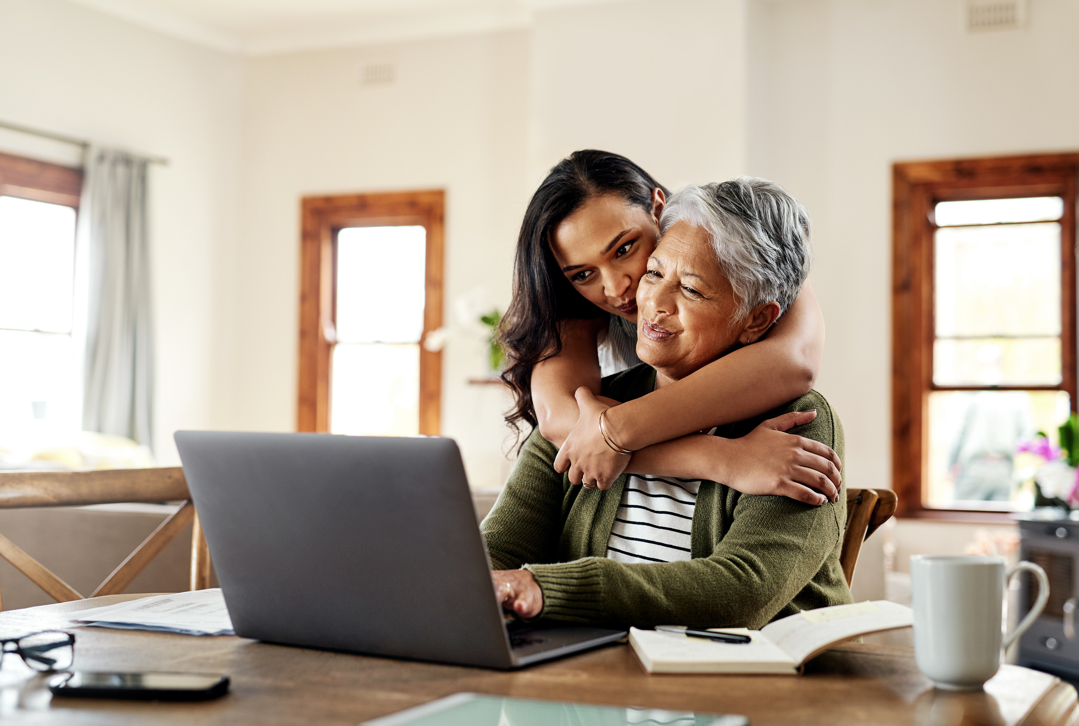 Two women are looking at resources on a laptop together.