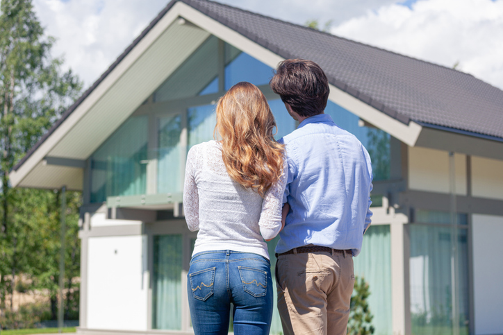 Husband and wife on a green lawn next to a new house